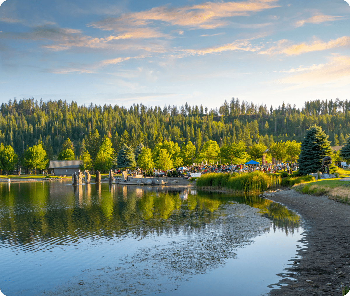 Lake with trees and people gathering nearby.